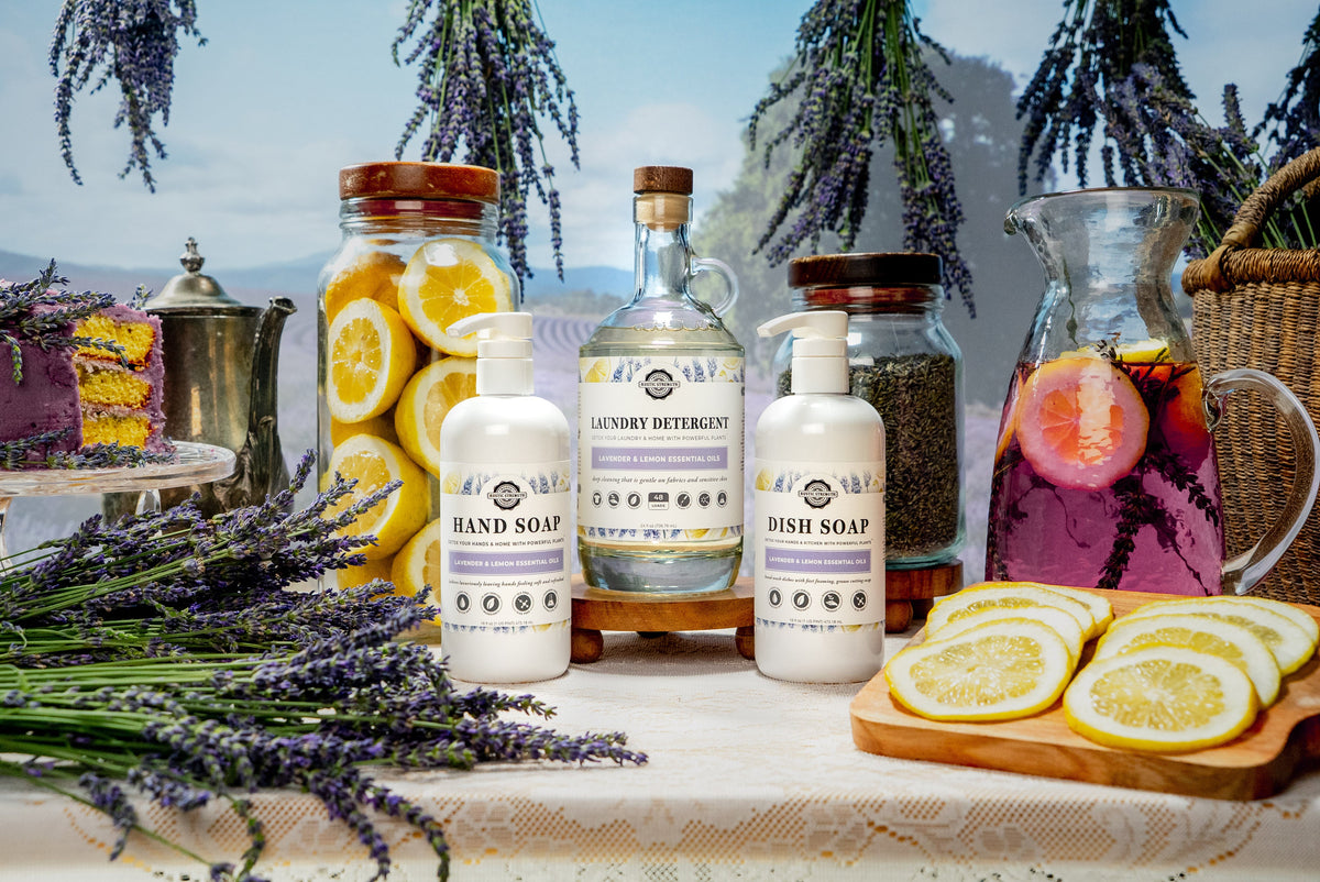 Rustic Strength, photoshoot image of Lavender & Lemon scented products surrounded by Lemons, Lavender Sprigs, a Lemon & Lavender Cake and a Purple Lemonade in a glass caraffe