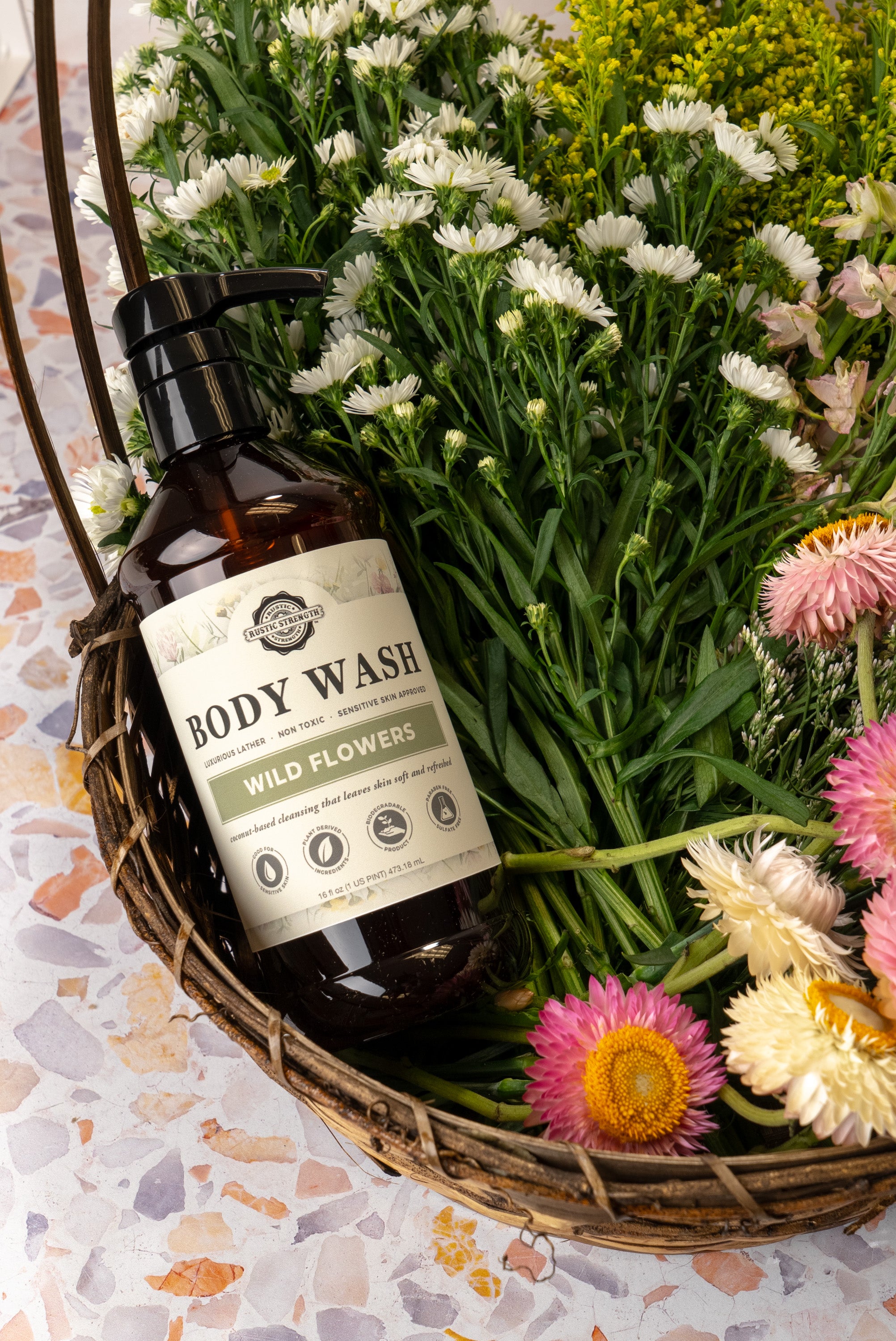 16 ounce plastic bottle of body wash in Wild Flowers scent, sitting in a basket of flowers