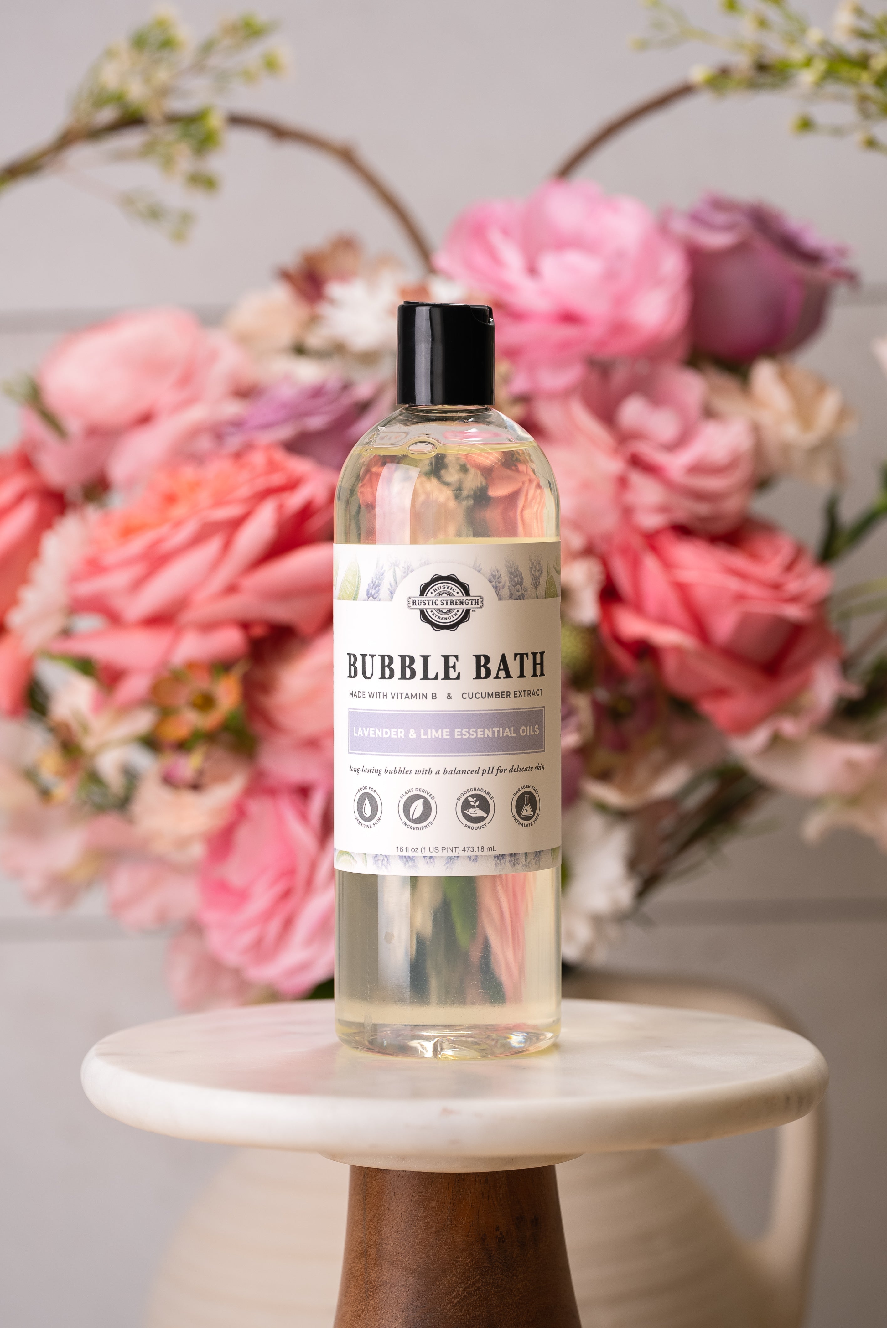 Bubble bath plastic bottle in Lavender and Lime Essential Oils scent with flowers in the background