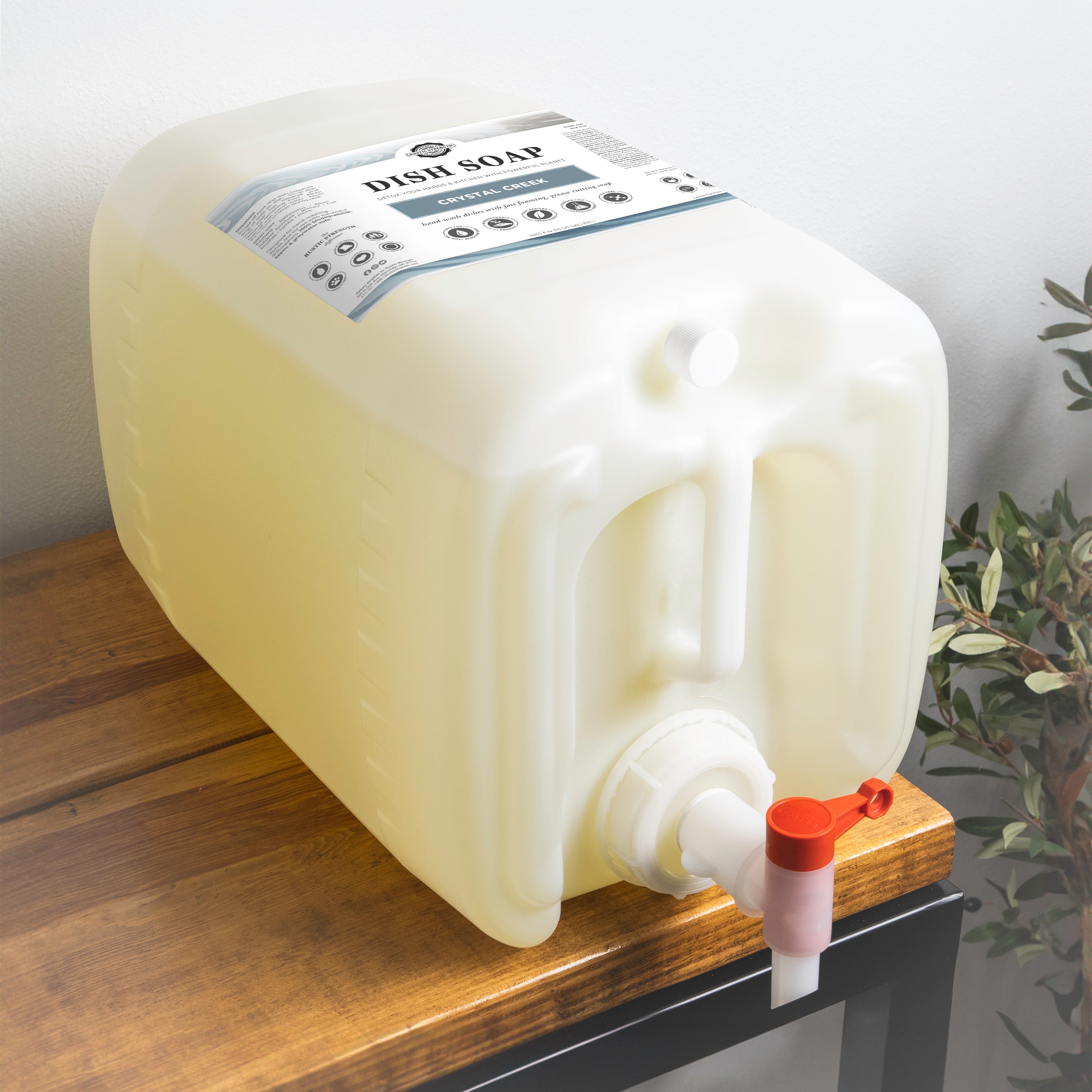 5 gallon container of Crystal creek scented of dish soap with a pump on a wooden surface.