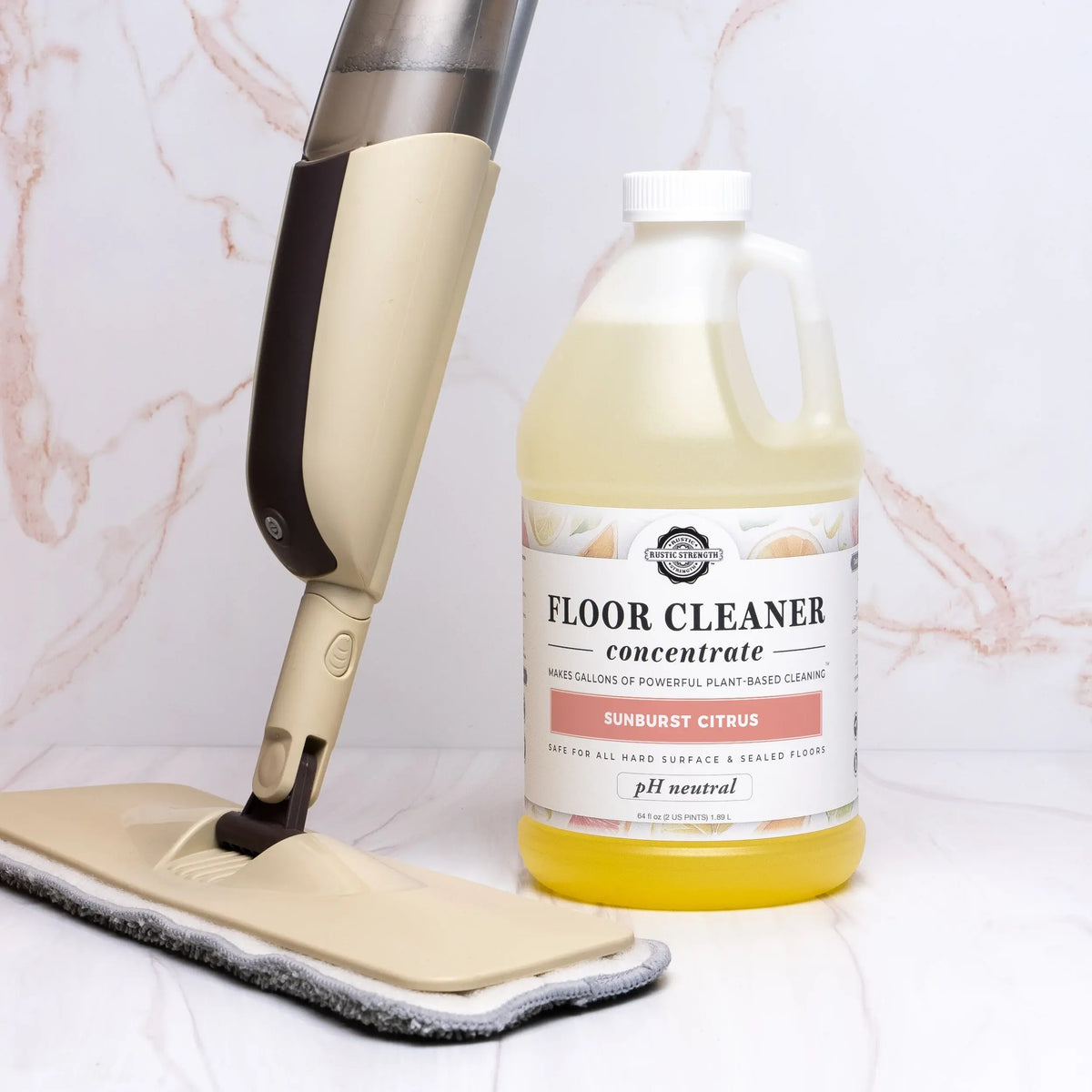 Rustic Strength, Floor Cleaner Concentrate lifestyle image picturing a Plastic Gallon of Floor Cleaner next to a Zero Waste Mop on a marbled background.