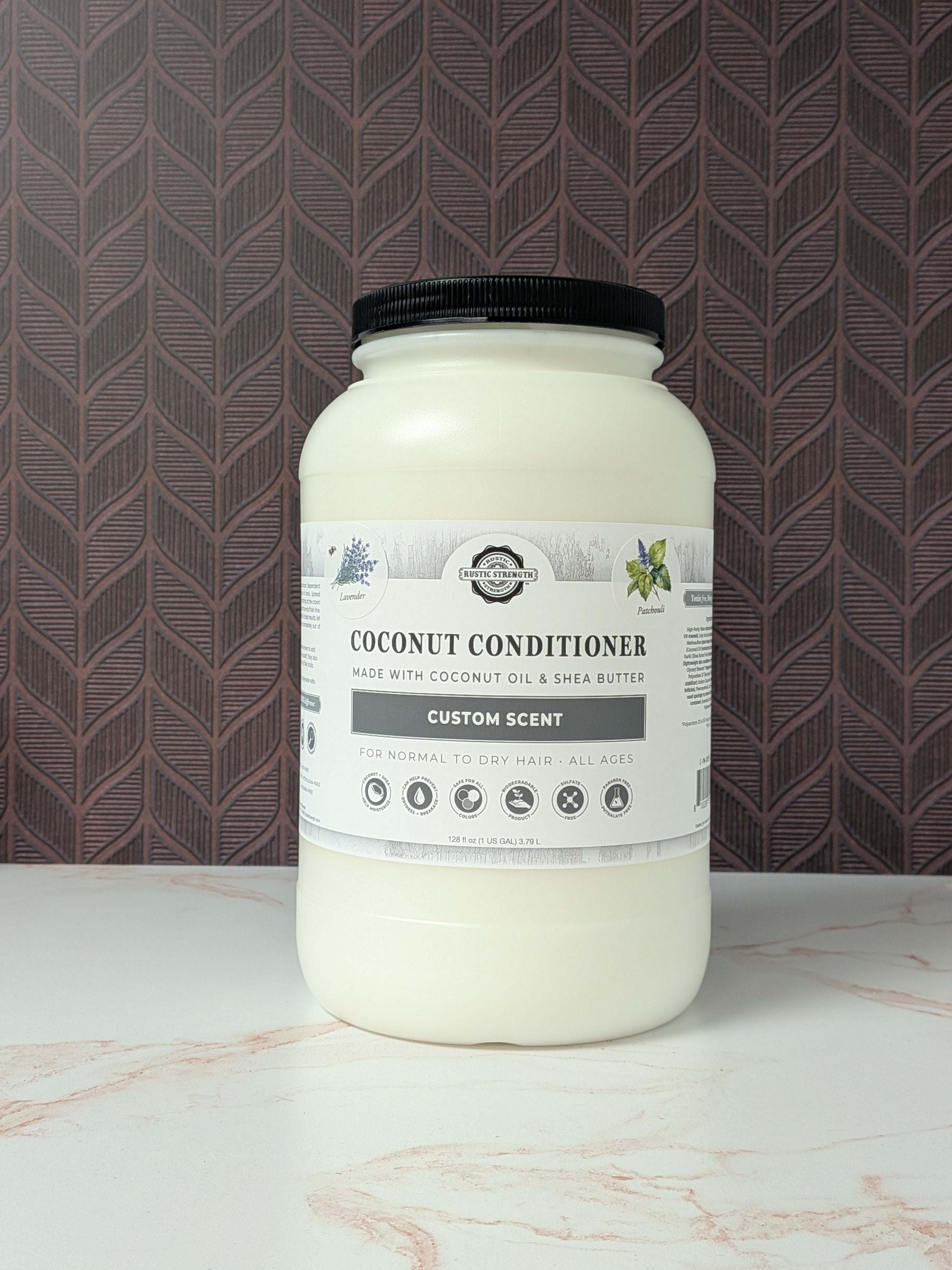 Gallon container of coconut conditioner jar with label on a marble surface and patterned wall background