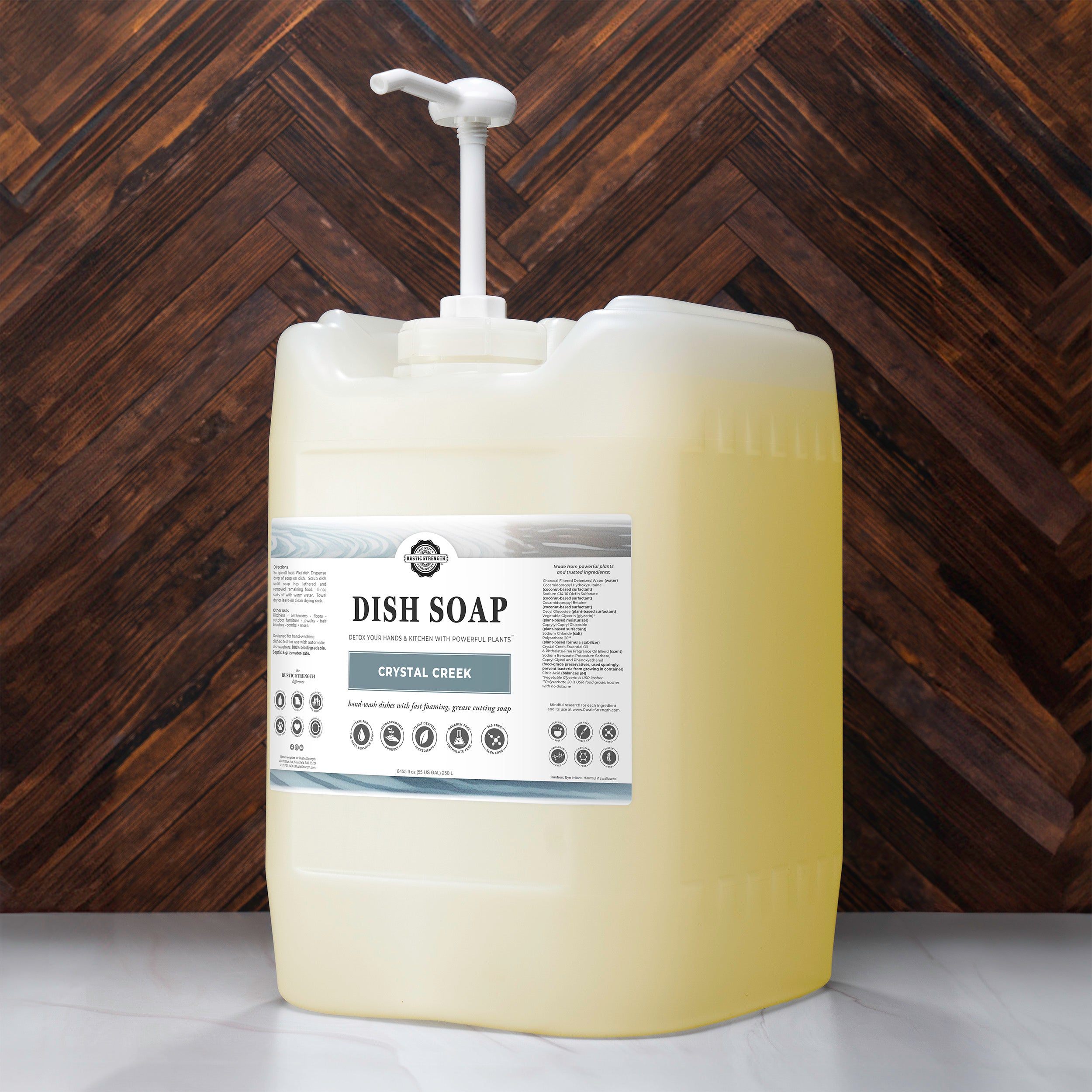 5 gallon container of Crystal Creek scented  dish soap with a pump on a wooden background